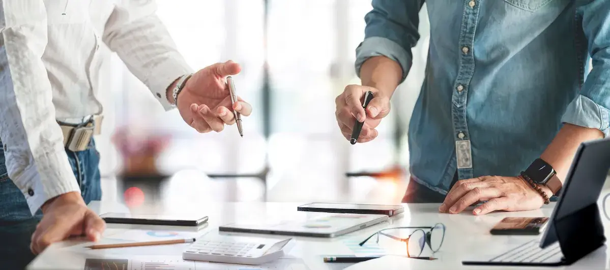 Two business partners leaning over a desk, both working on the same papers