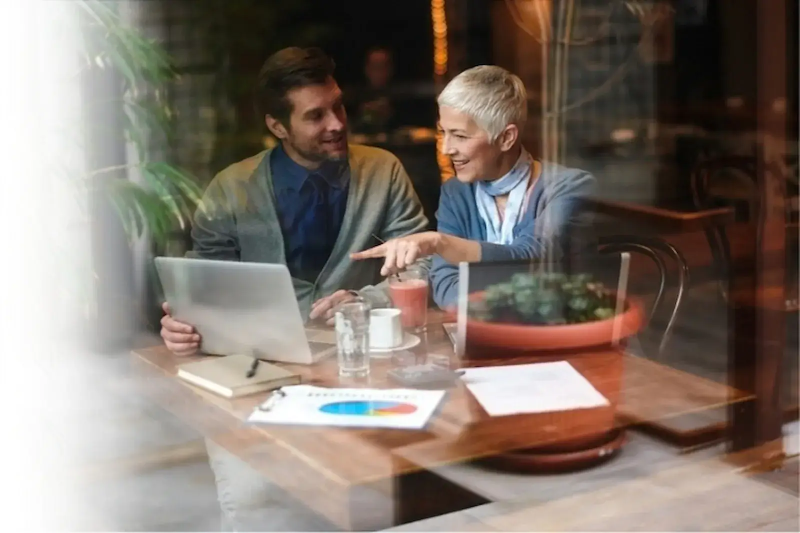 Two business partners talking over a laptop at a cafe table