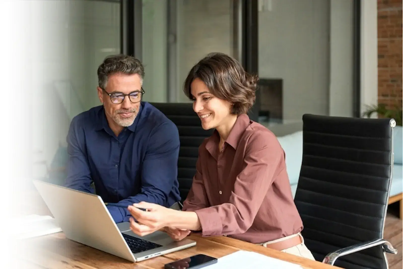 Two business partners at a shared desk looking at the same screen