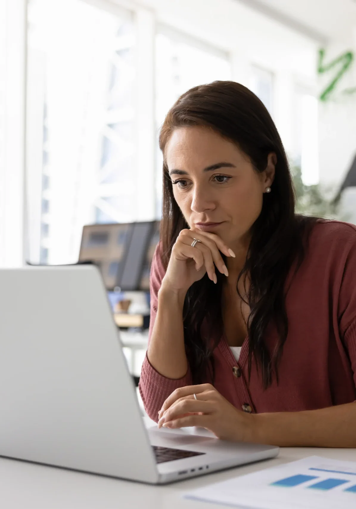Thoughtful serious female entrepreneur working at laptop in office
