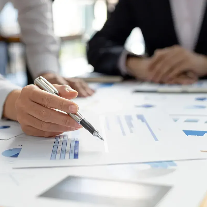 business-partners-reviewing-printed-charts Two people reviewing printed charts together, one pointing with a pen